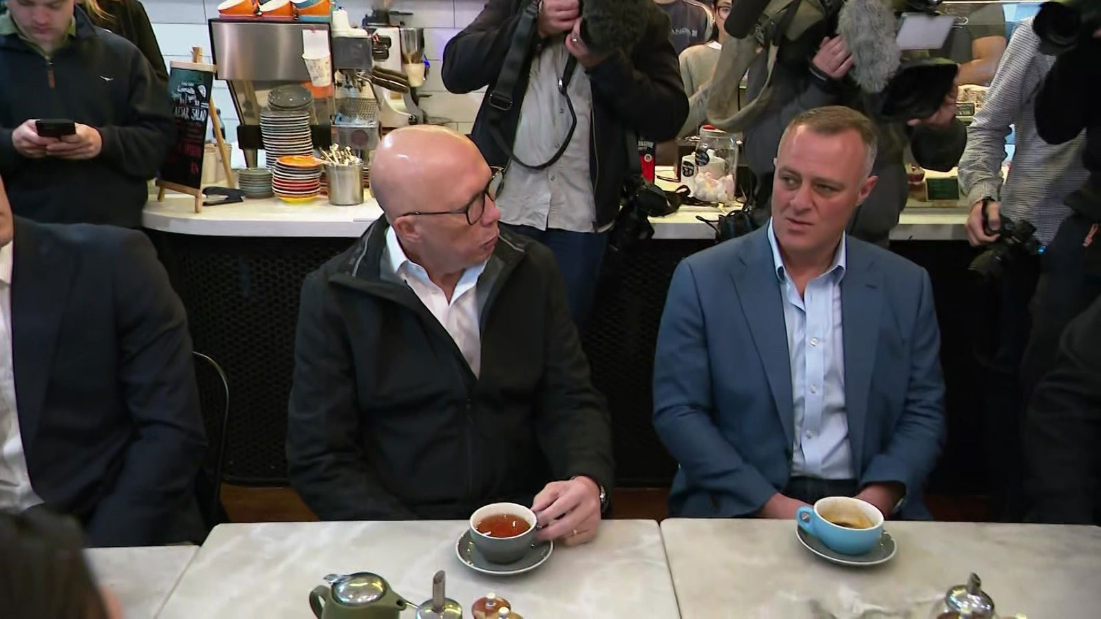 Peter Dutton sitting next to Tim Wilson at a cafe table with two cups of tea