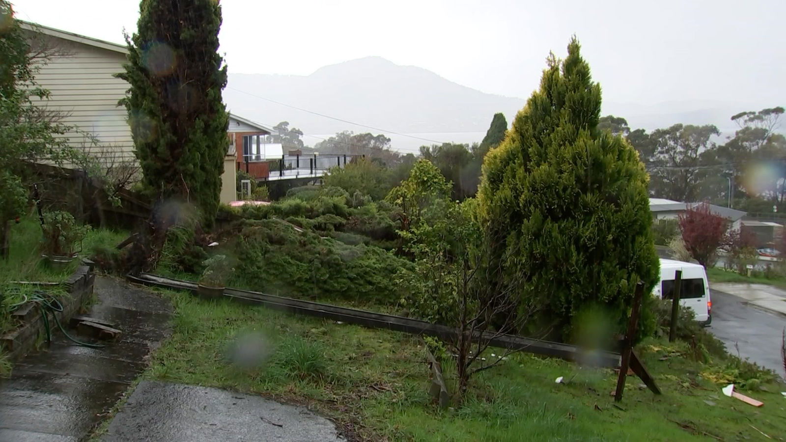 A long piece of guttering lying in a front yard.