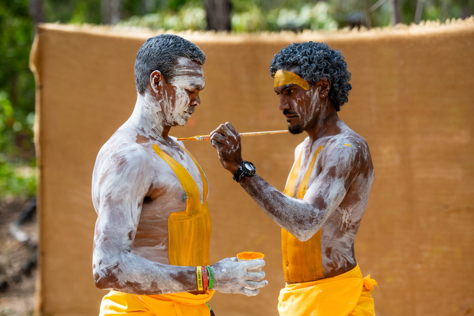 Two men in white and yellow body paint.