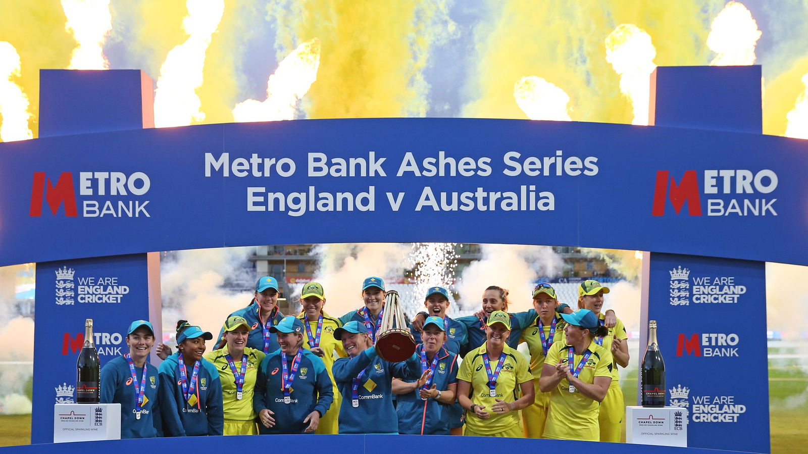 Australia celebrate winning the Ashes, holding a trophy in front of a blue structure.