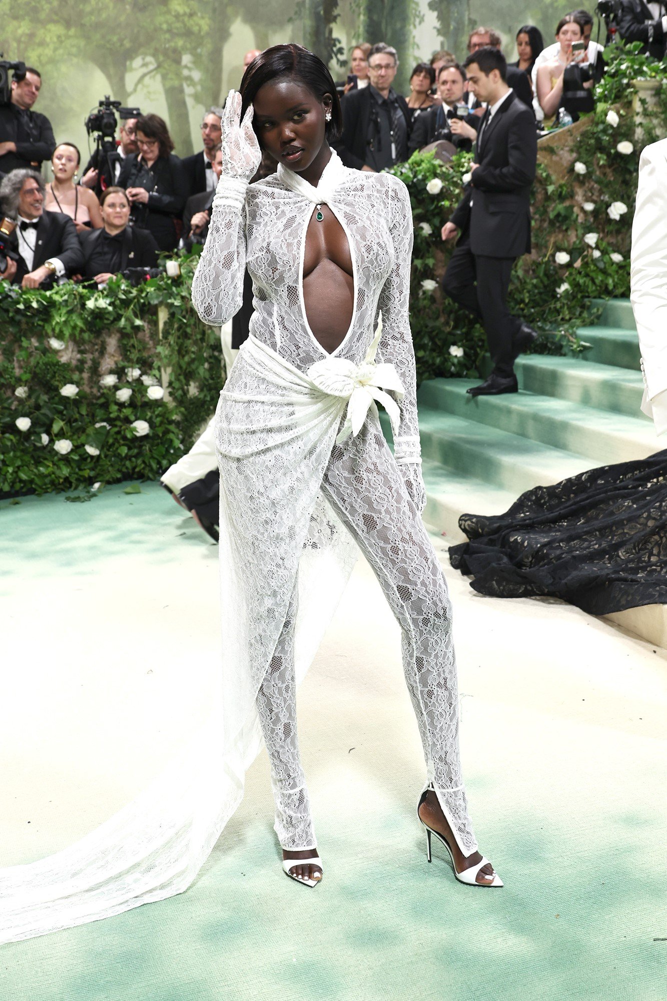 Adut wears a lacey white body suit with a slid down the chest.