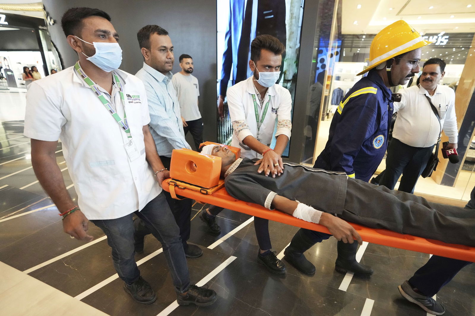 Four men carry another out on a stretcher in a mock drill