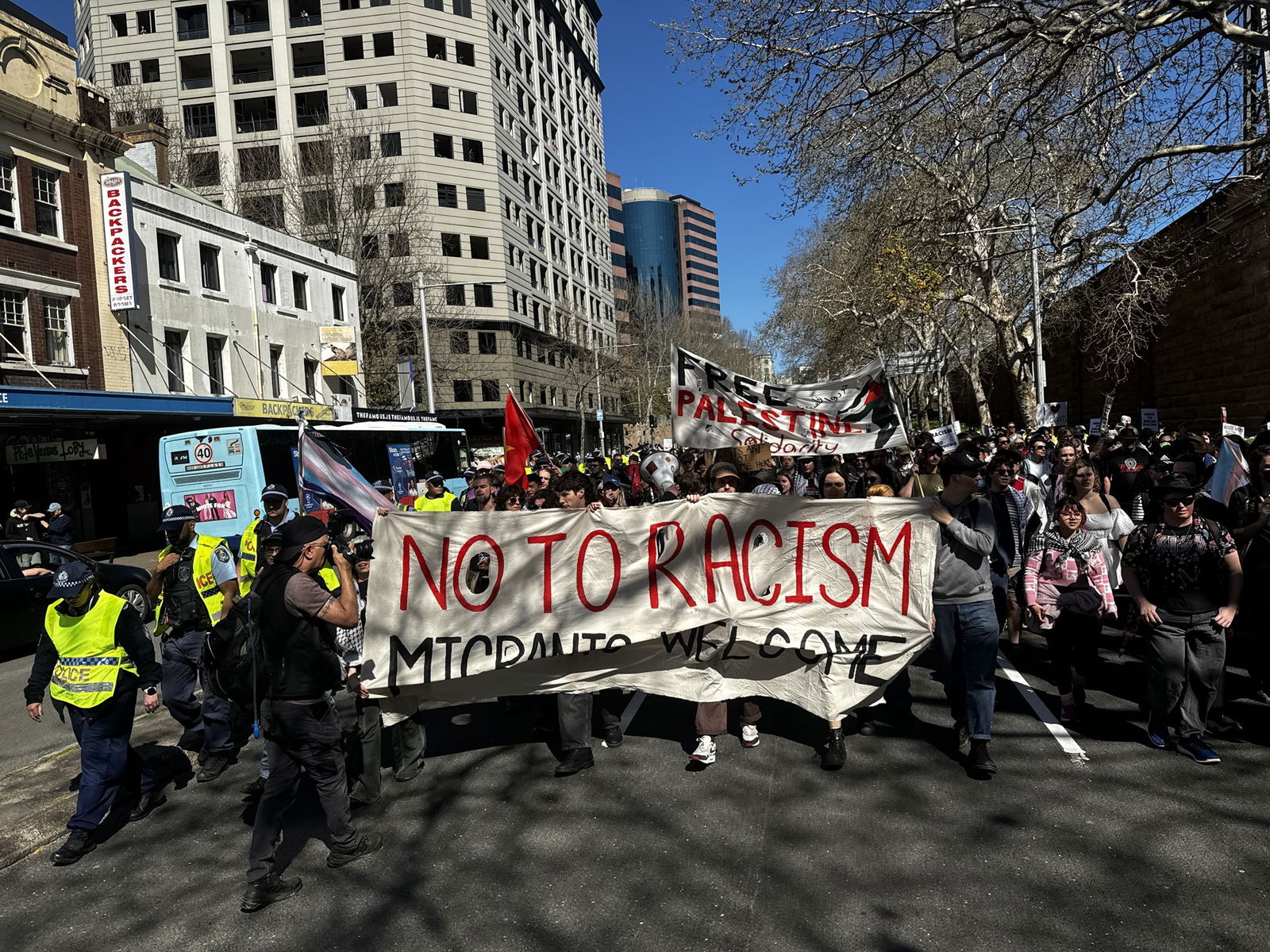 Personas que marchan detrás de un banner pro-migración