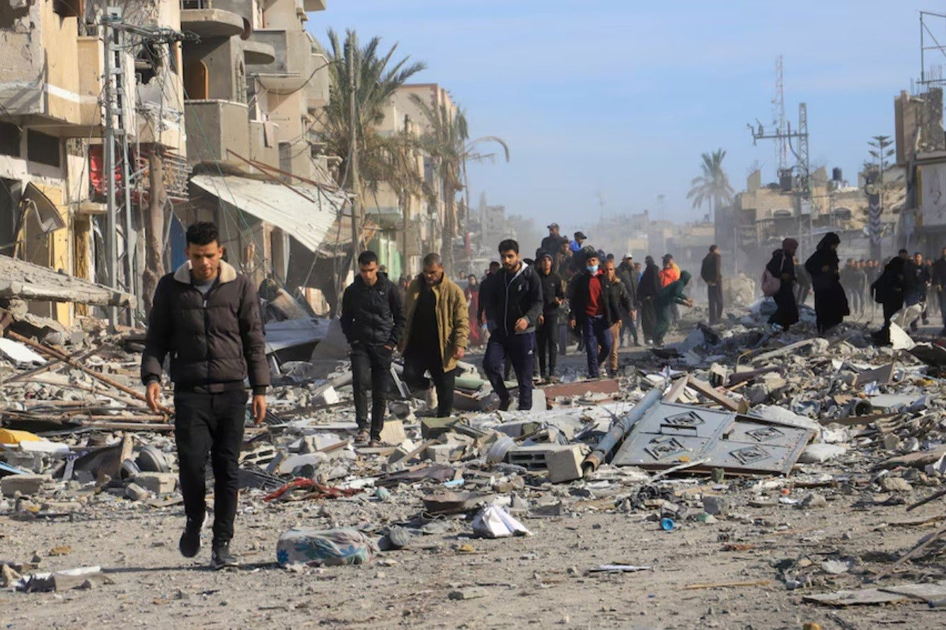 Several people walking over rubble.