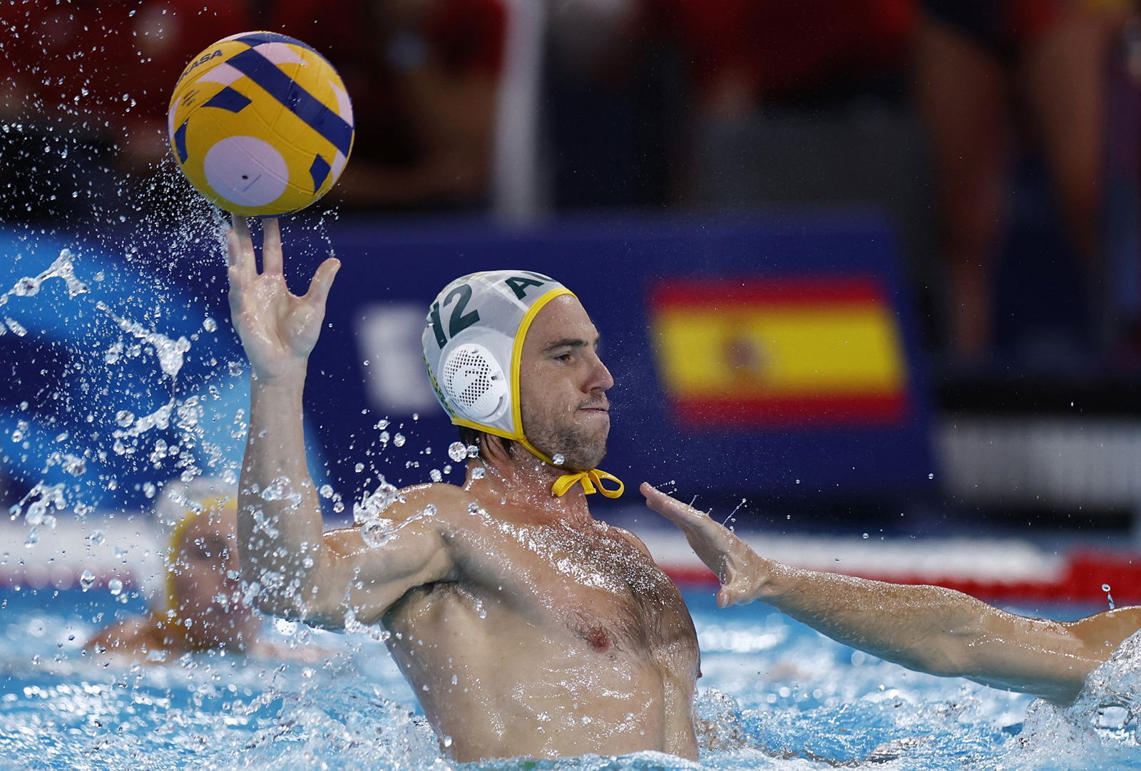 A water polo player, with their upper body out of the water, prepares to catch the ball in the pool
