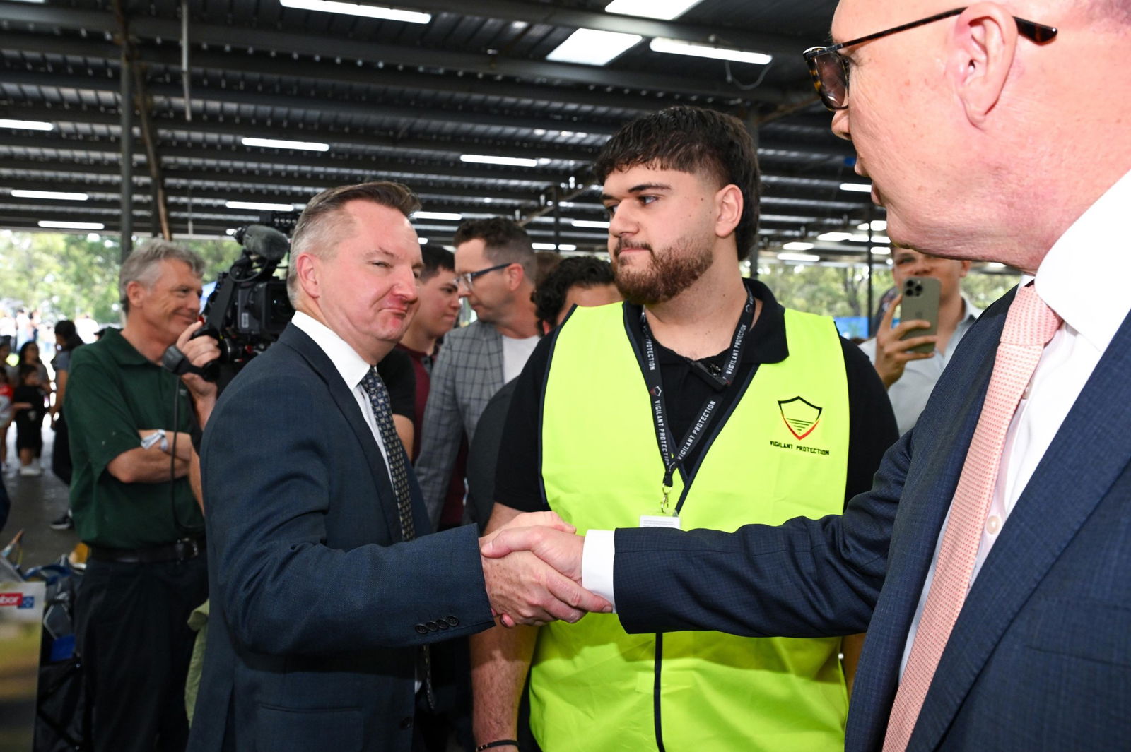 Chris Bowen appears to grimace as he shakes Peter Dutton's hand.