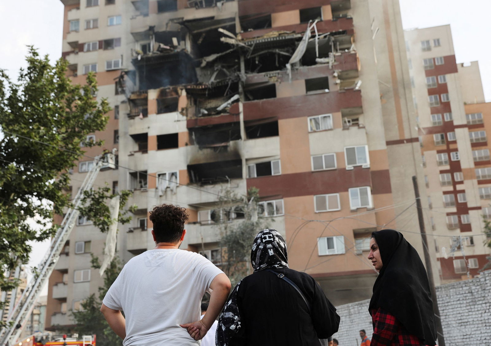 Trois personnes regardent un trou dans un bâtiment 