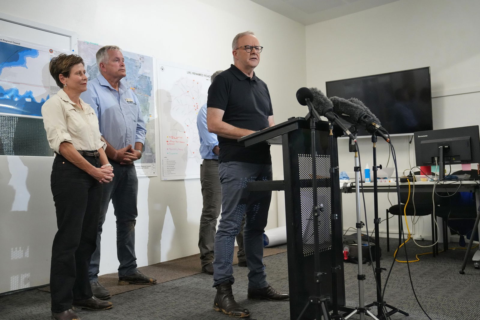 The PM stands behind a lectern and speaks to the media.