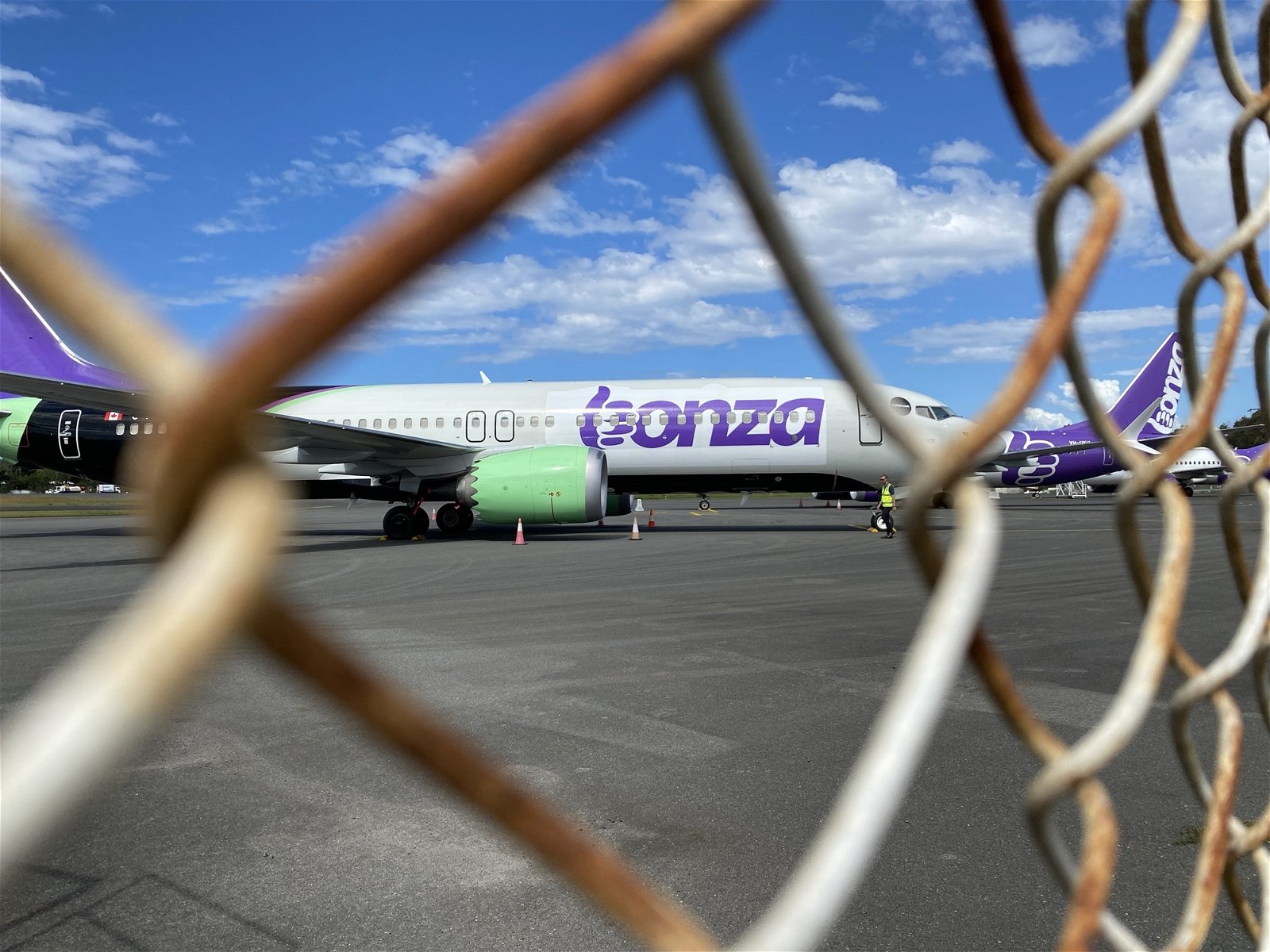 Image of Bonza airplane behind a gate.