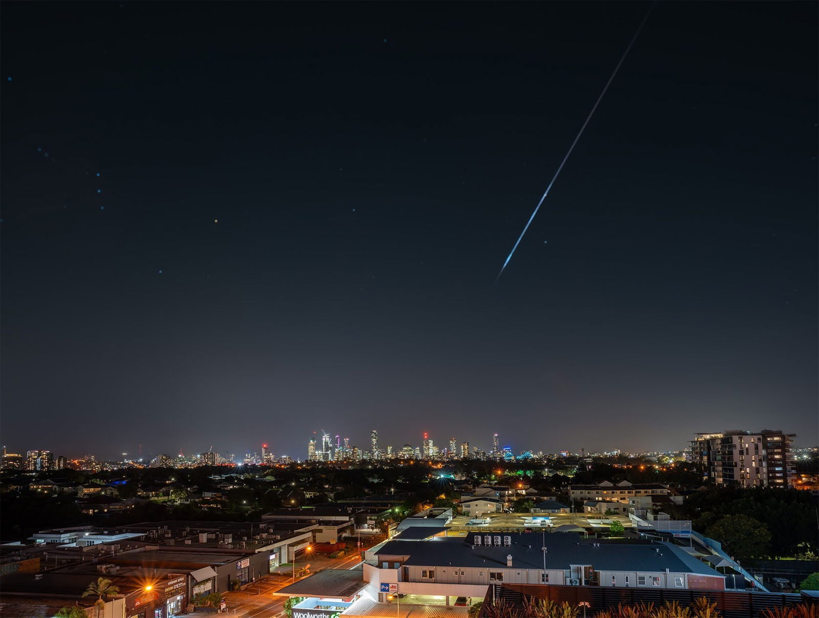 A shooting star falls over a city CBD 