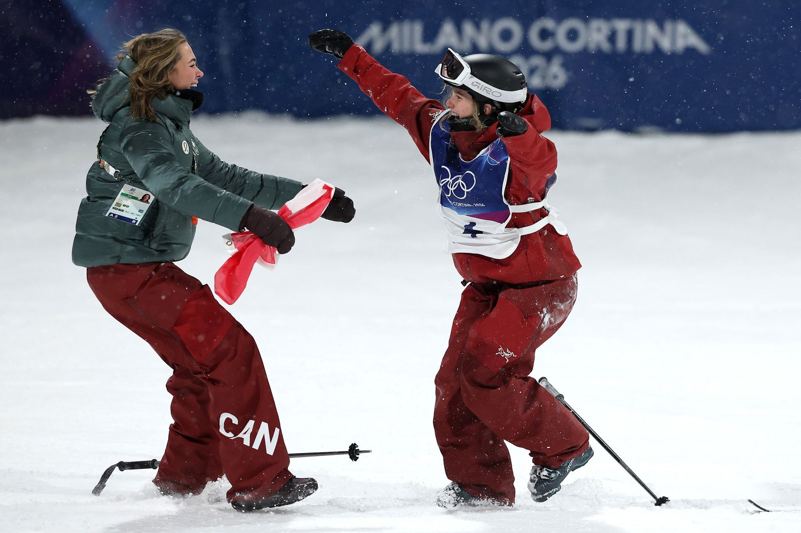 A skier in red is hugged by another skier