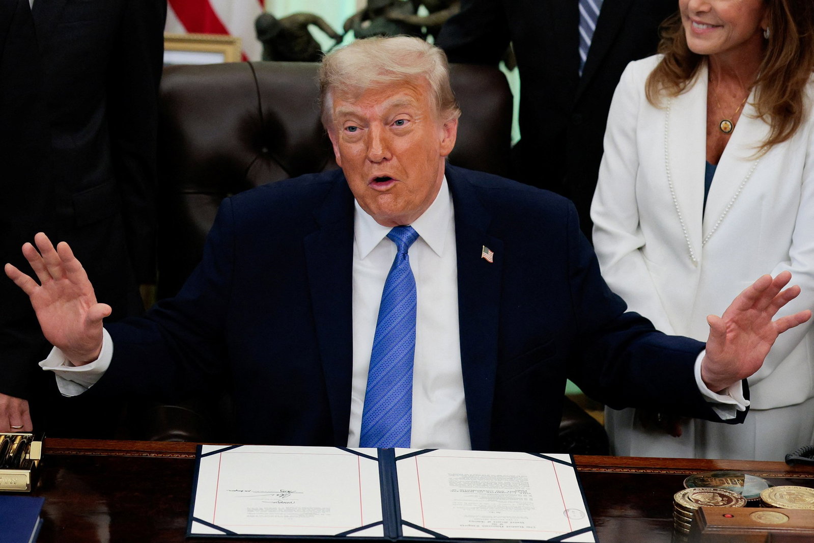 A man in a suit and blue tie sitting at a desk