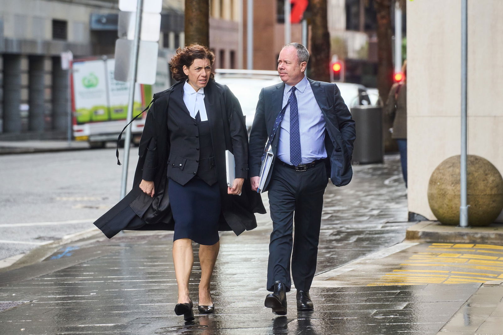 Lawyer Sue Chrysanthou in black robes walks outside court with a man in suit