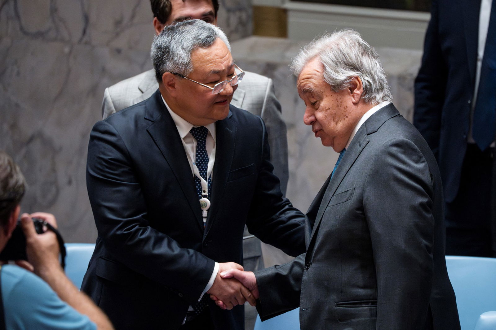 Two men in grey suits shake hands 