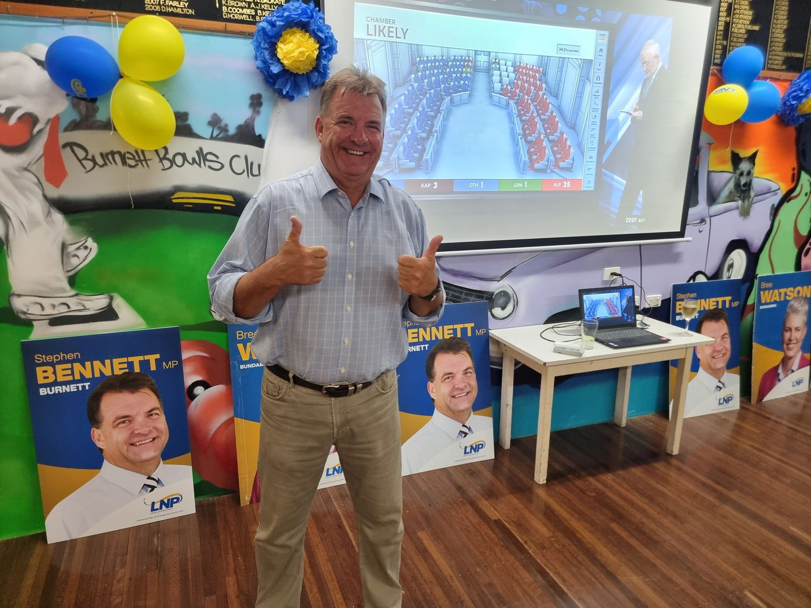 A man in a blue button-up smiles for the camera.