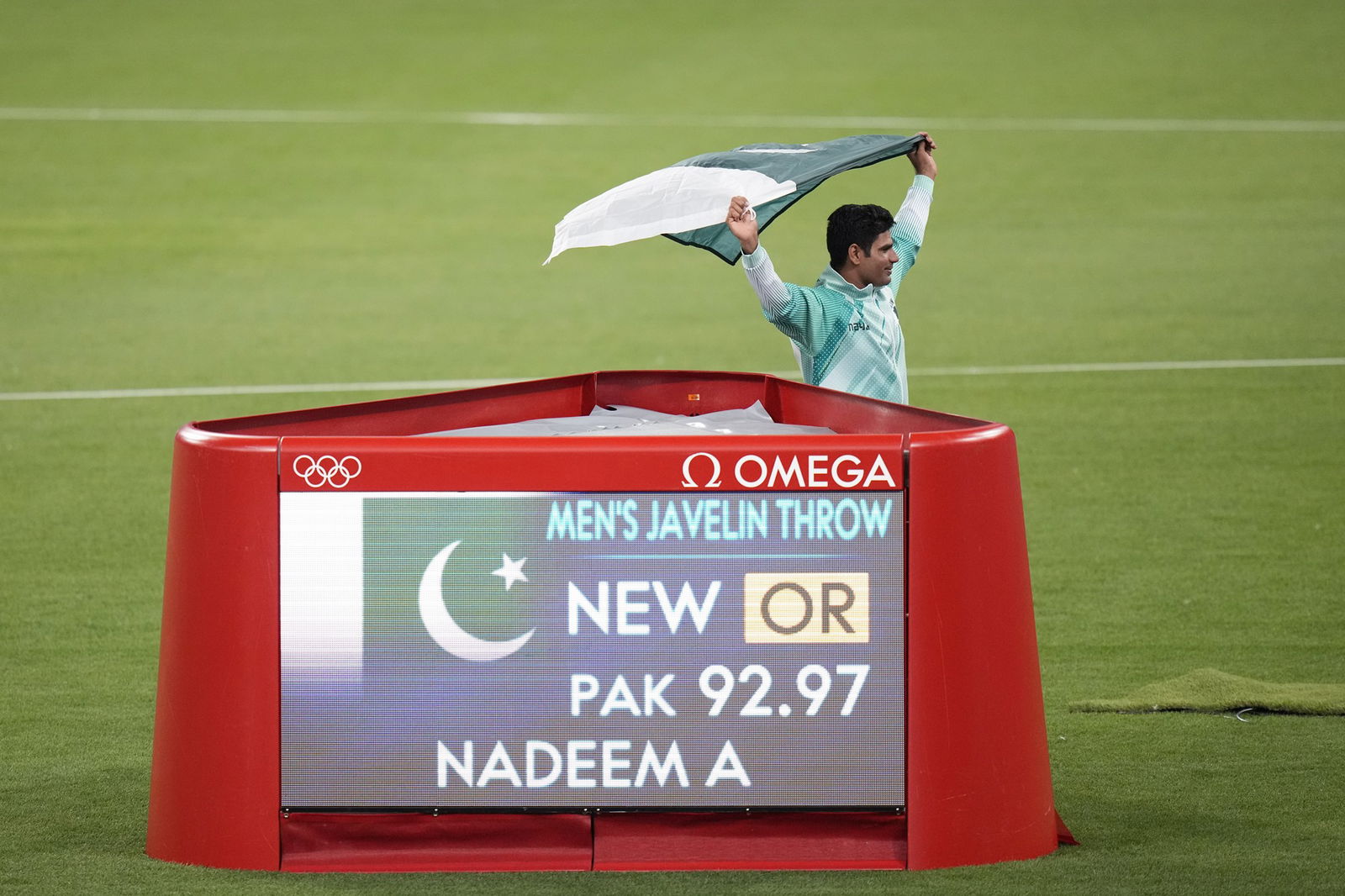 Pakistan javelin thrower Arshad Nadeem stands next to a scoreboard after his gold medal win in Paris.