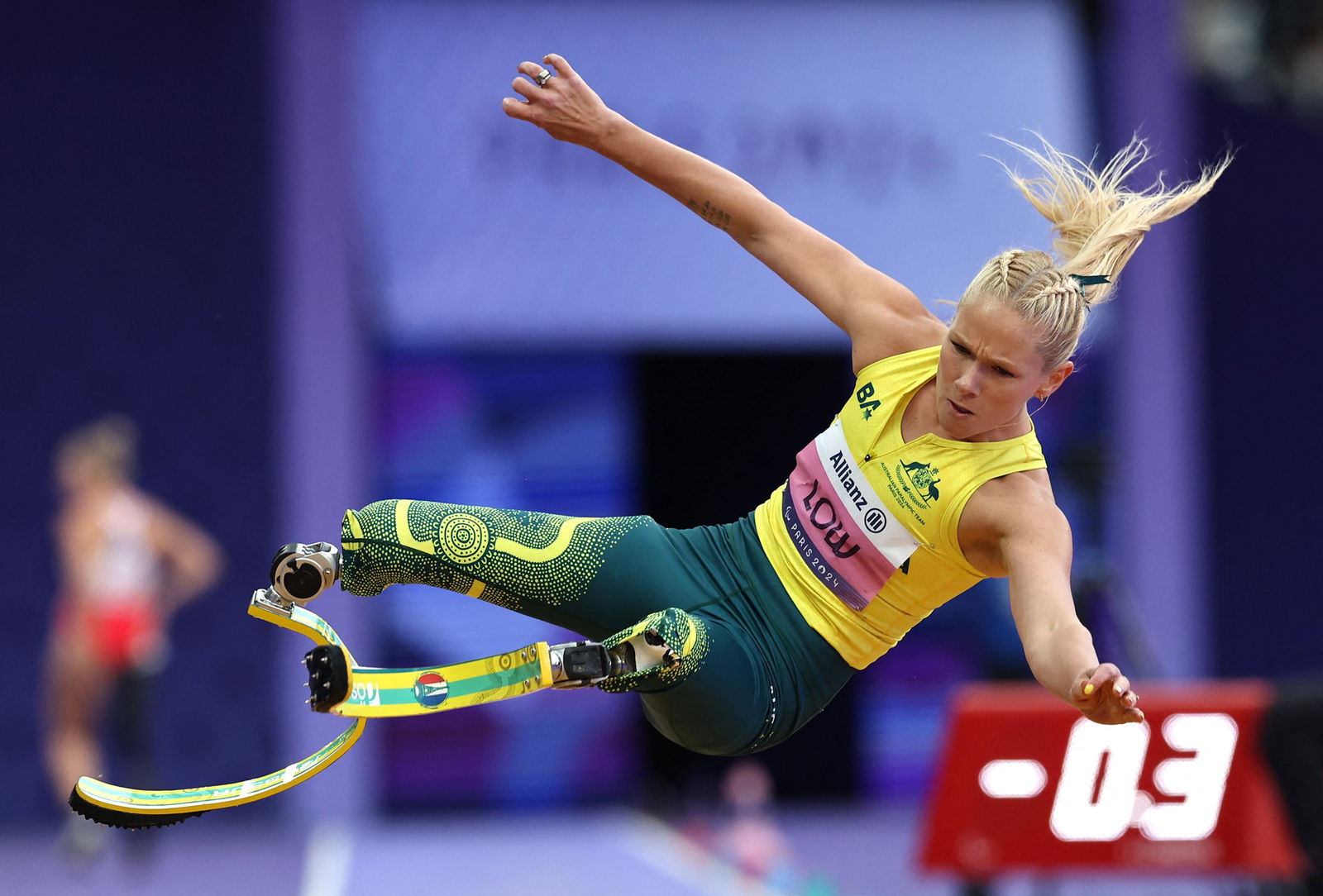 Vanessa Low jumping through the air, preparing to land in the sand pit