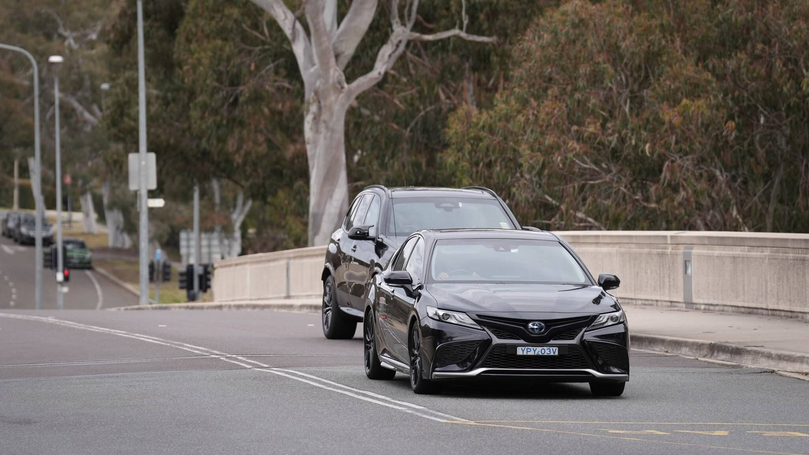 A black car drives up a ramp to parliament hosue.