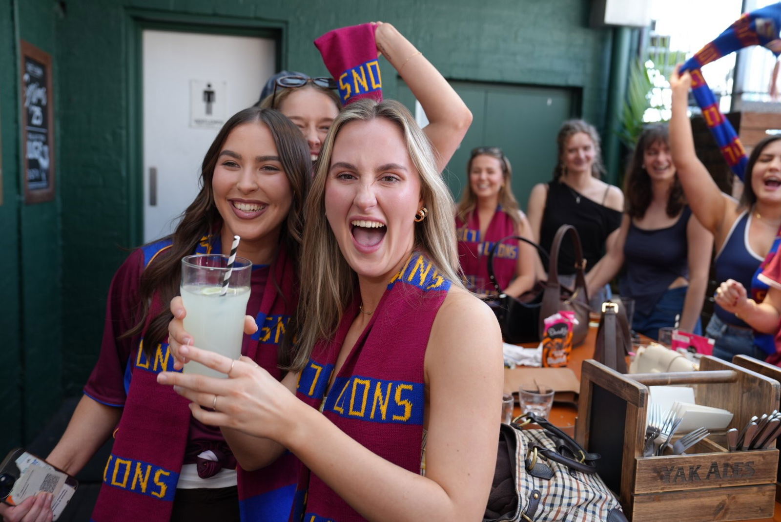 Jess and Eden smile, dressed in Brisbane Lions attire.