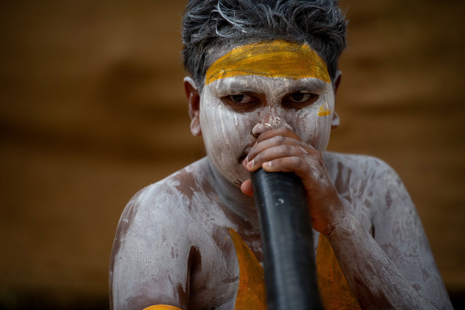 A young boy  in white and yellow body paint.