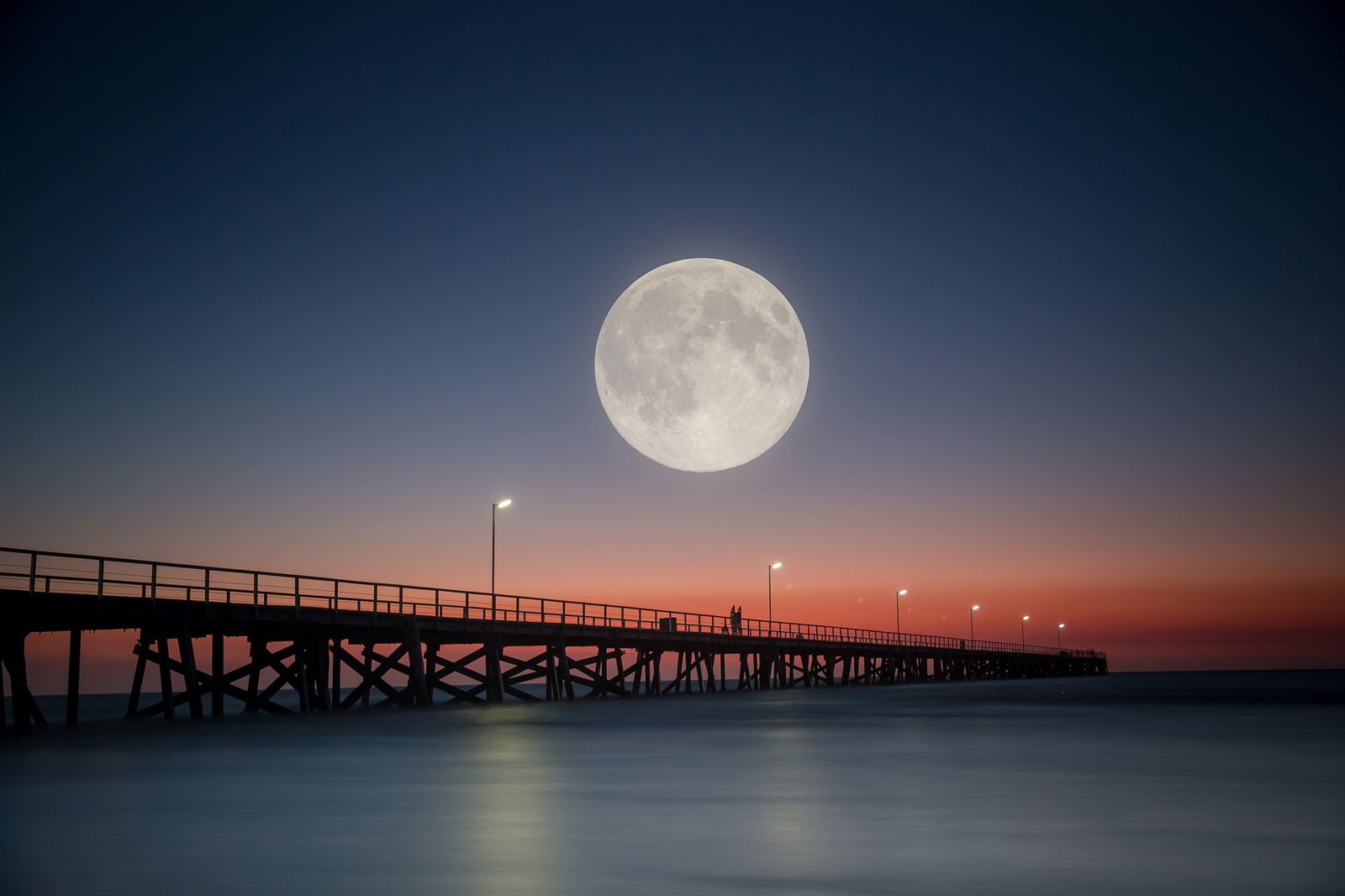 The moon seen in the sky over a pier