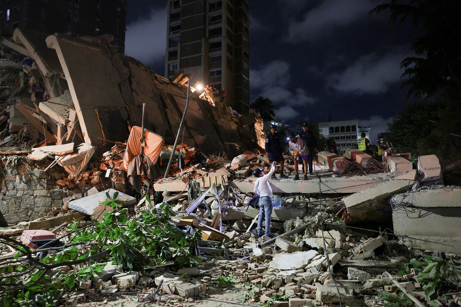 Emergency services work at the site of a collapsed building.
