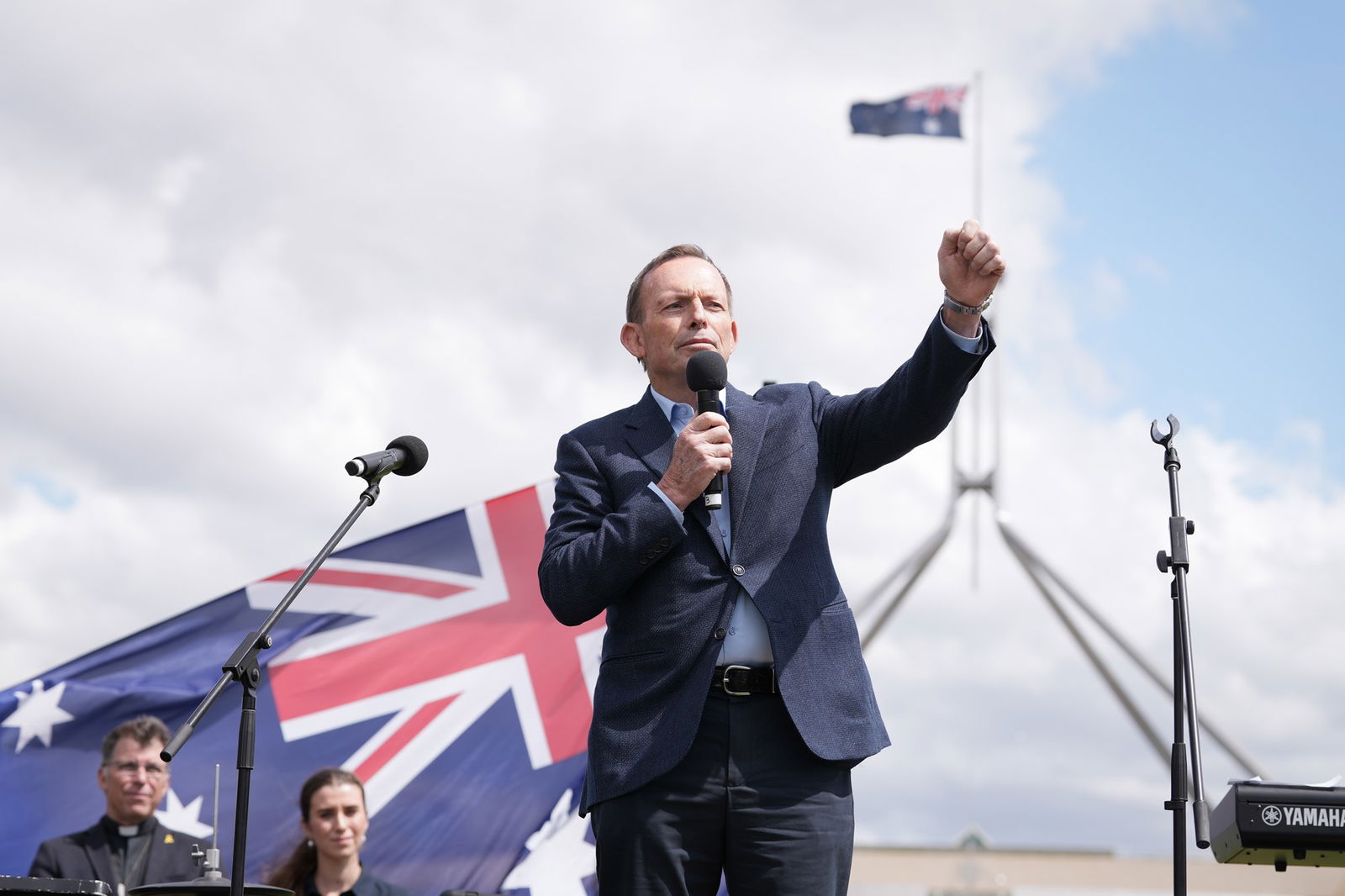 Tony Abbott in front of an Australian flag punching a fist in the air. 