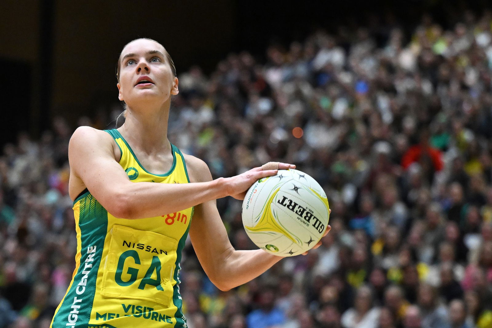 A player holds the ball on the side of her body and looks up to the post