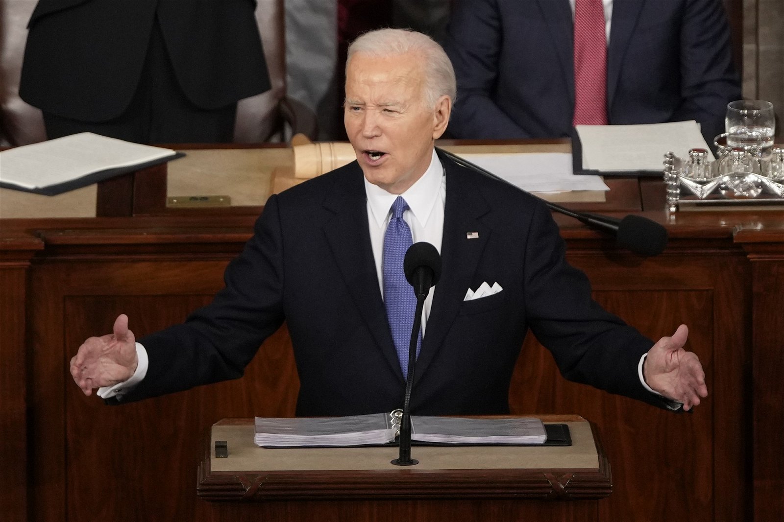 Joe Biden holds his arms out wide either side of the microphone