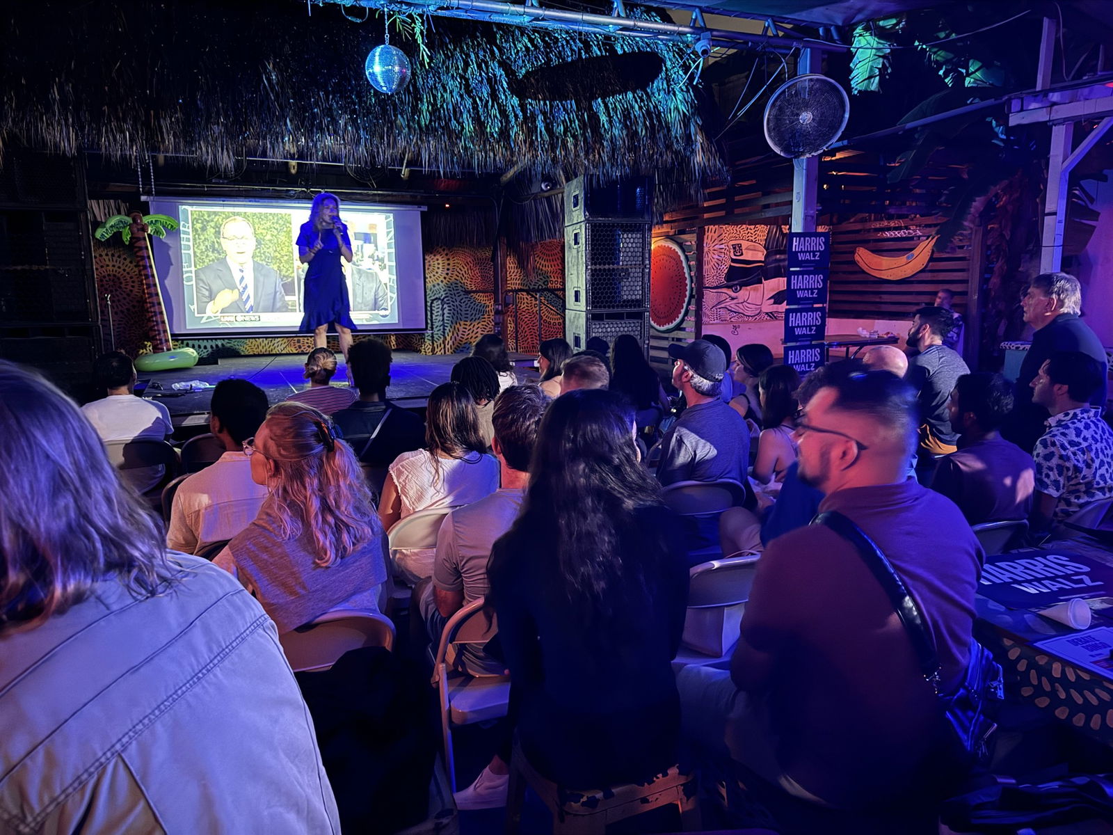 a small crowd watches a woman on stage in a bar