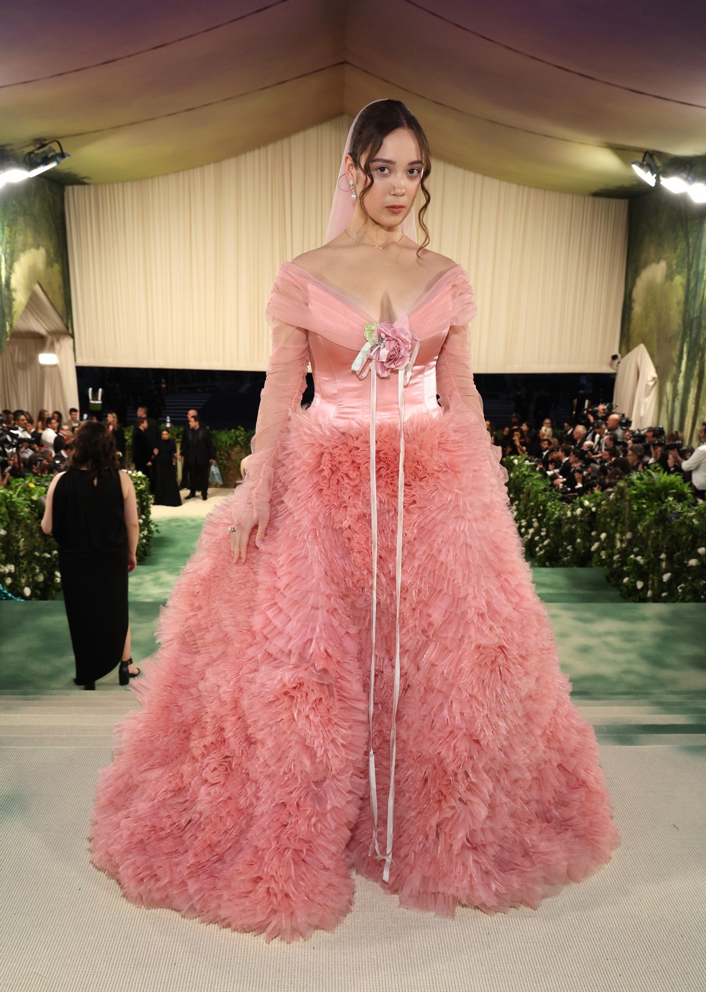 Laufey wears a pink fluffy gown with a giant flower at her chest.