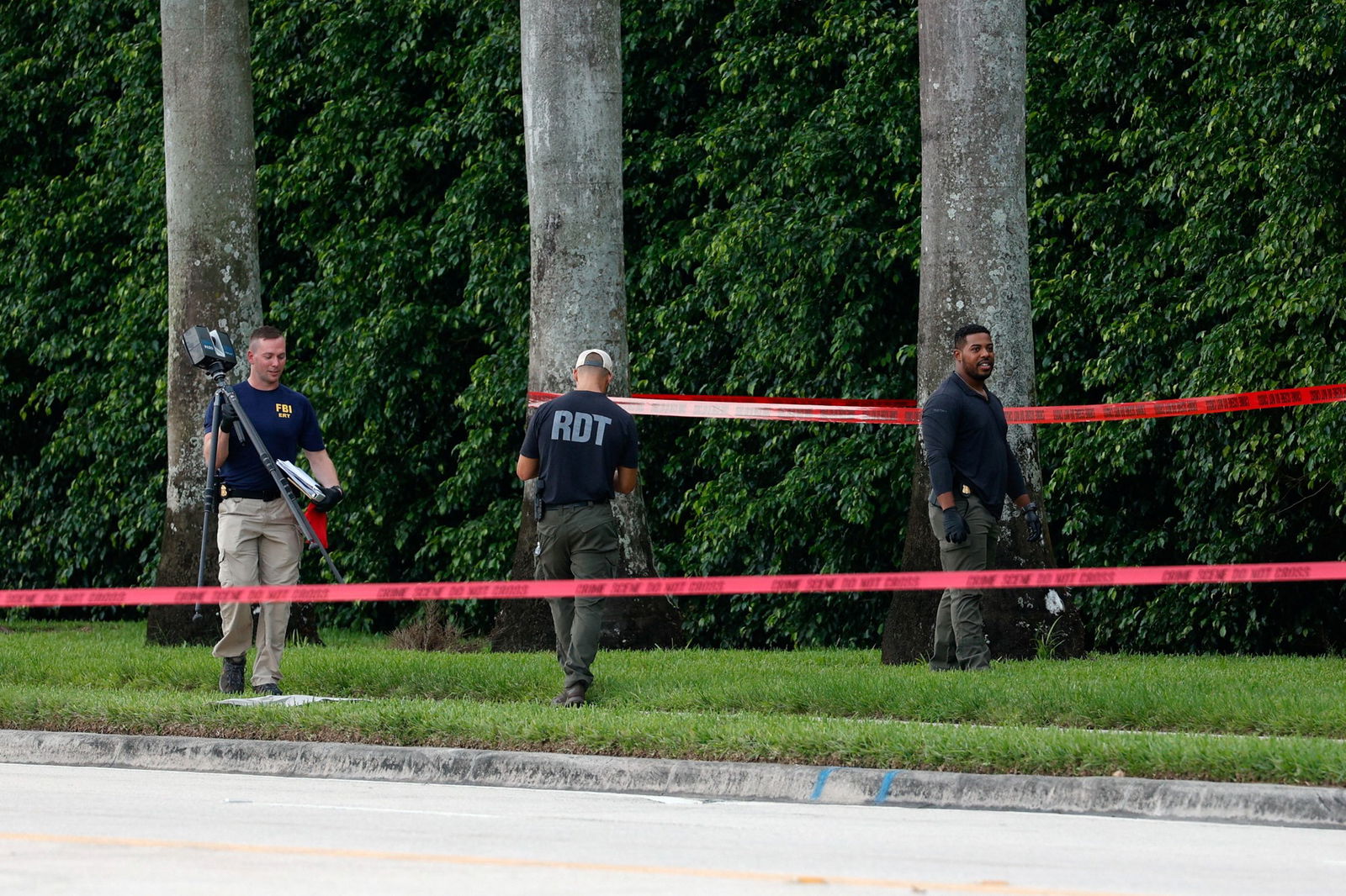 Police officers work behind police tape outside a golf course