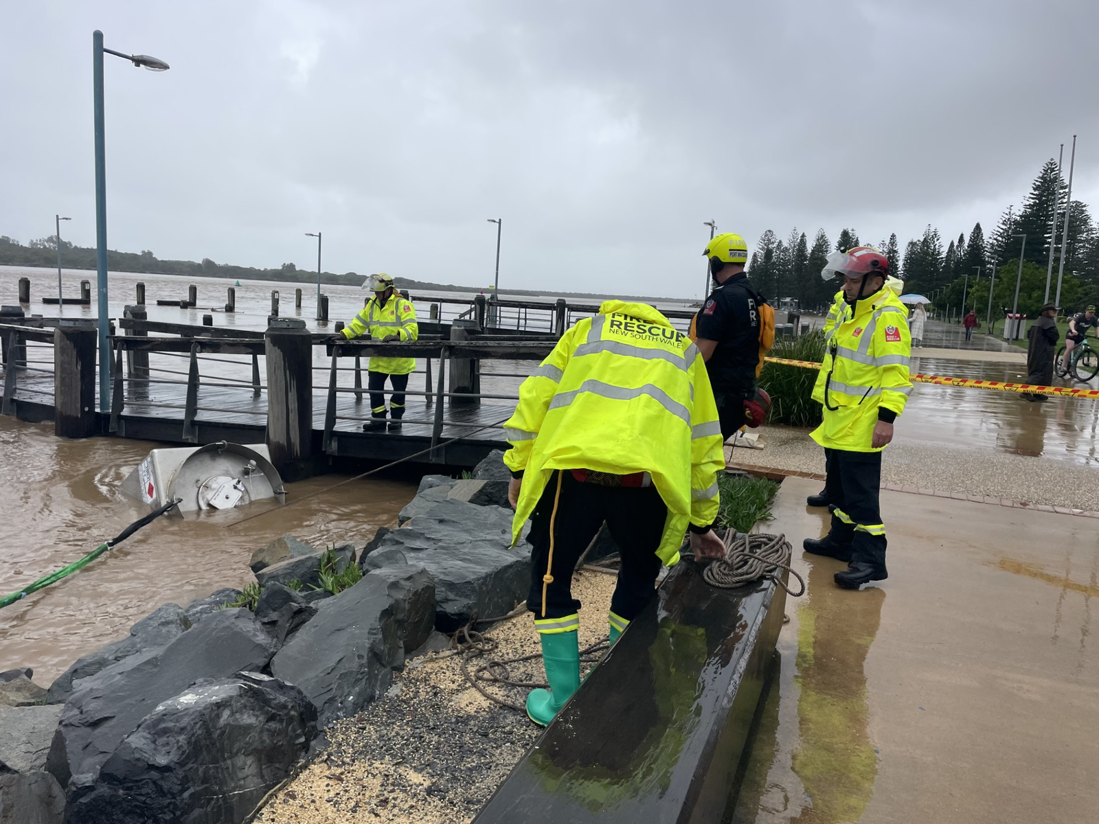 People in neon yellow jackets examine an aviation tank in a river