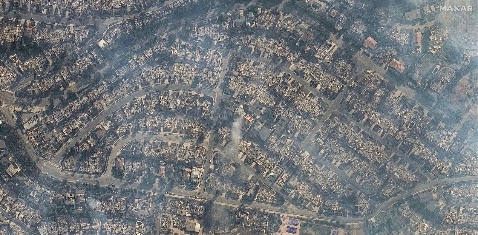 An aerial view of the Pacific Palisades, blackened and covered in smoke