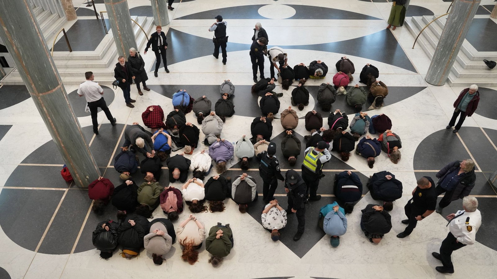Protests kneel with their hands behind the backs.