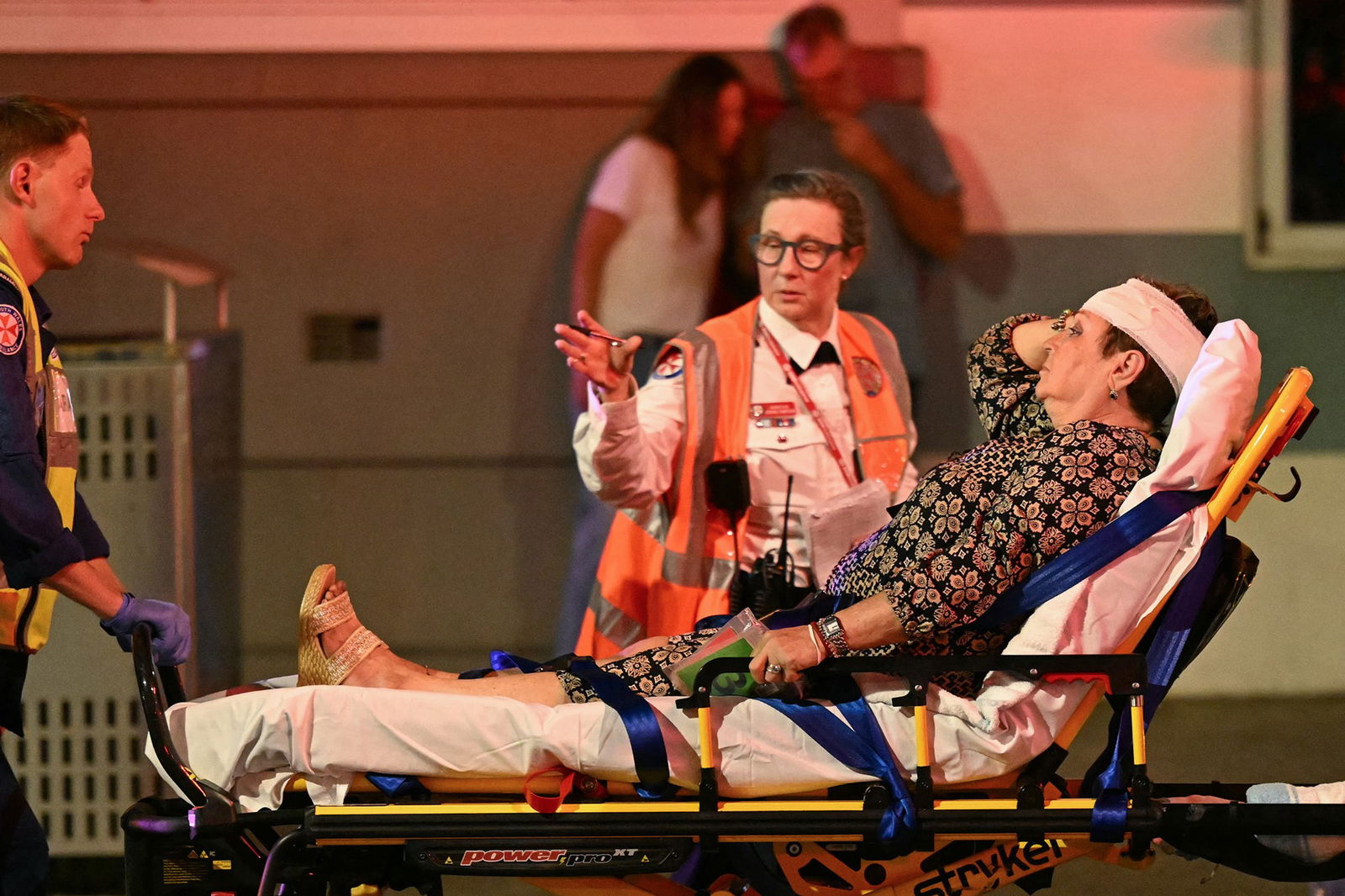 Health workers move a woman on a stretcher to an ambulance after a shooting incident at Bondi Beach in Sydney on December 14, 2025
